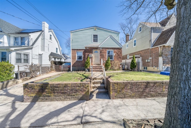 view of front of home featuring brick siding, a fenced front yard, and a front lawn