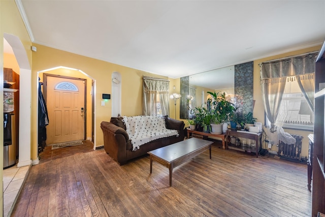living area with crown molding, arched walkways, and hardwood / wood-style floors