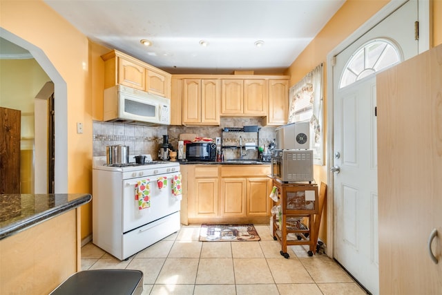 kitchen with tasteful backsplash, white appliances, light tile patterned floors, light brown cabinetry, and a sink