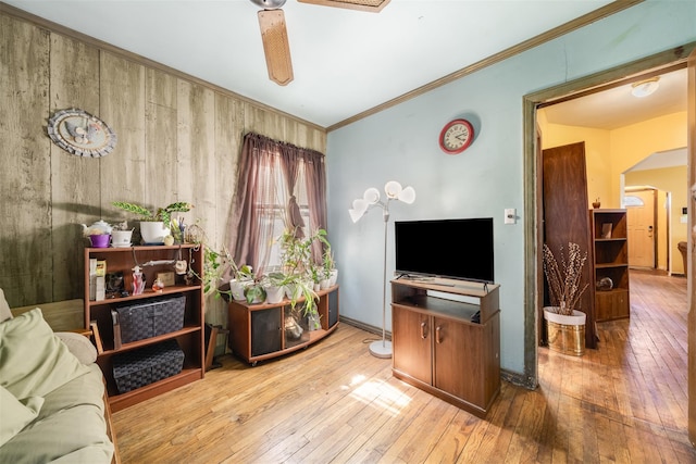 living area with hardwood / wood-style floors, ornamental molding, baseboards, and a ceiling fan