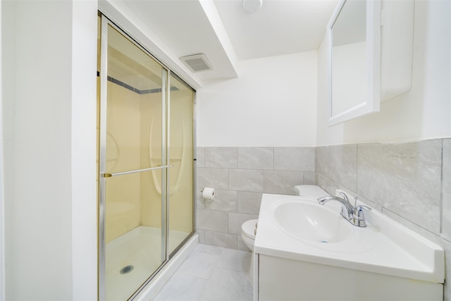bathroom featuring tile walls, toilet, a stall shower, and vanity