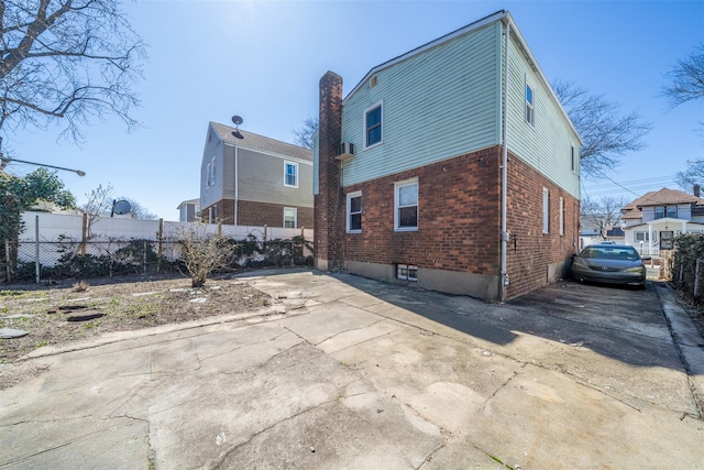 back of property featuring fence, brick siding, and a patio