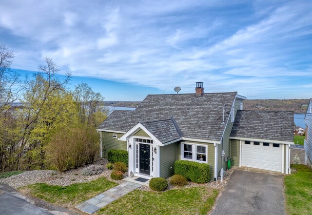 view of front facade featuring a front lawn, an attached garage, a chimney, and aphalt driveway
