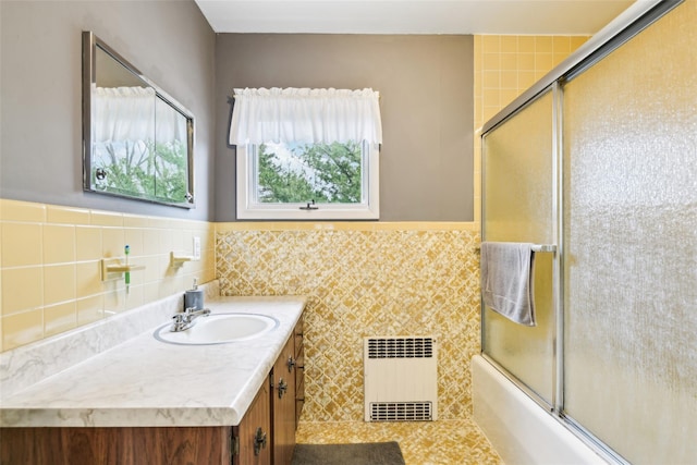 36 Seaview Ave, Northport, NY 11768 - full bath featuring a wainscoted wall, vanity, radiator heating unit, bath / shower combo with glass door, and tile walls