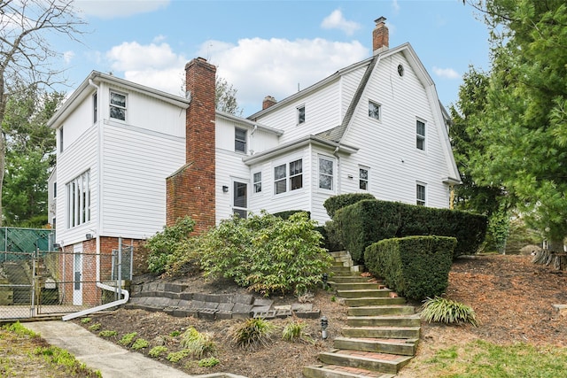 36 Seaview Ave, Northport, NY 11768 - rear view of property featuring a gambrel roof, fence, stairs, and a chimney