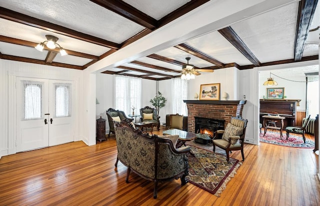 430 Montauk Hwy, East Moriches, NY 11940 - living area with a brick fireplace, ceiling fan, beamed ceiling, french doors, and hardwood / wood-style floors