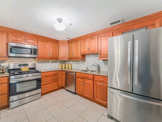 kitchen with light tile patterned floors, visible vents, decorative backsplash, stainless steel appliances, and a sink