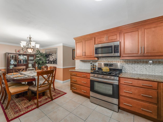 kitchen with tasteful backsplash, an inviting chandelier, ornamental molding, brown cabinetry, and stainless steel appliances
