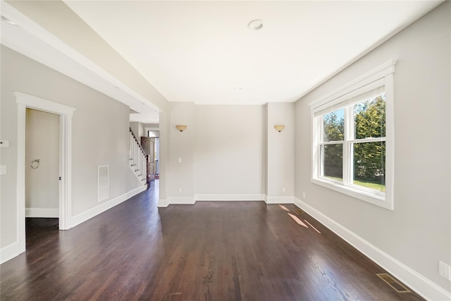 unfurnished living room featuring baseboards, dark wood-type flooring, stairway, and visible vents