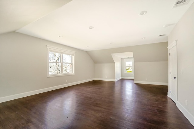 bonus room featuring dark wood-type flooring, baseboards, vaulted ceiling, and visible vents