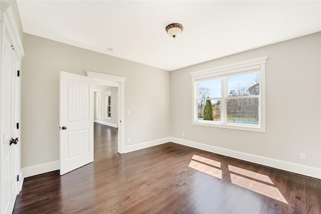 empty room featuring visible vents, baseboards, and wood finished floors