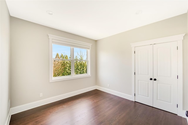 unfurnished bedroom with baseboards and dark wood finished floors
