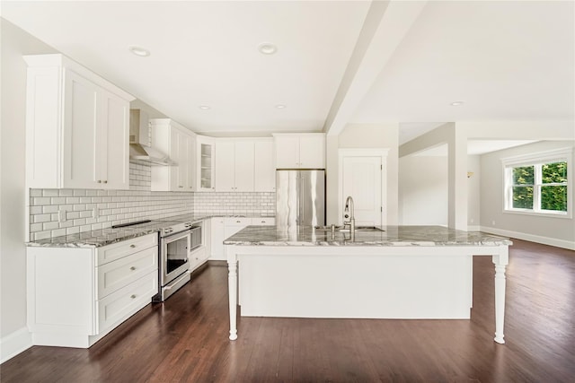 kitchen with a kitchen bar, a sink, appliances with stainless steel finishes, and wall chimney exhaust hood