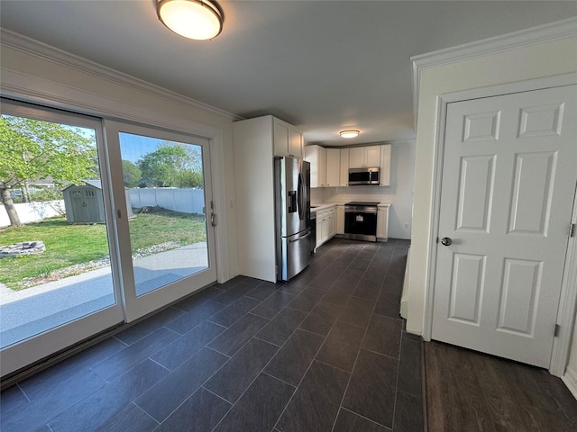 kitchen featuring light countertops, stainless steel appliances, white cabinetry, and ornamental molding