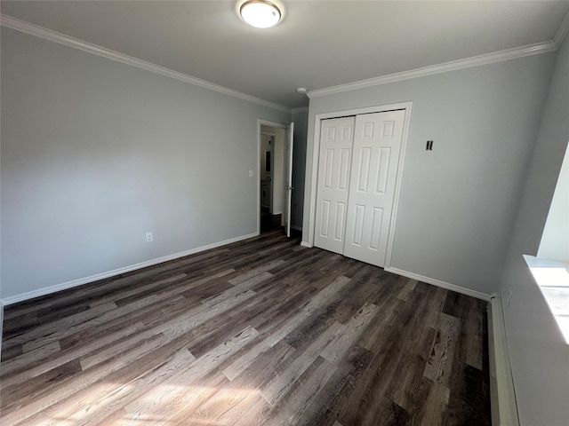 unfurnished bedroom with baseboards, ornamental molding, a closet, and dark wood-style floors