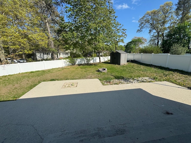 view of yard with an outdoor structure, a fenced backyard, a patio area, and a storage shed