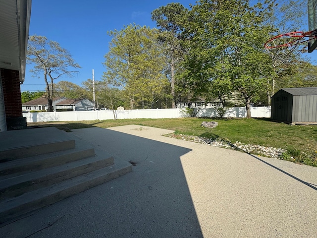 view of yard with an outbuilding, a fenced backyard, a patio area, and a storage unit