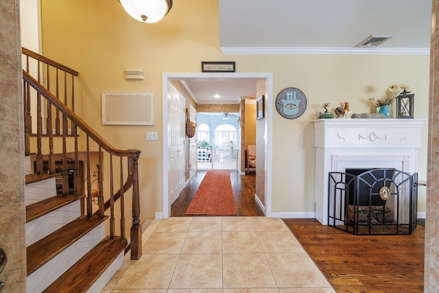 foyer featuring crown molding, stairs, wood finished floors, and visible vents