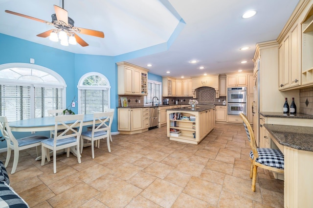 kitchen featuring decorative backsplash, ceiling fan, appliances with stainless steel finishes, open shelves, and cream cabinetry