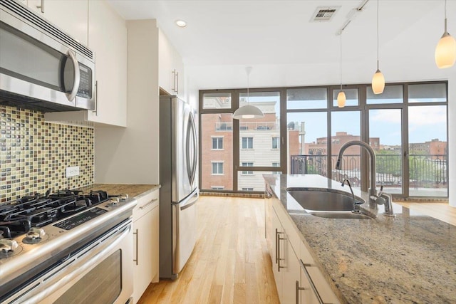 412 Kings Hwy Unit 6C, Brooklyn, NY 11223 - kitchen featuring stainless steel appliances, a sink, white cabinetry, backsplash, and light wood-style floors