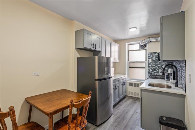 kitchen with freestanding refrigerator, gray cabinetry, radiator heating unit, and a sink