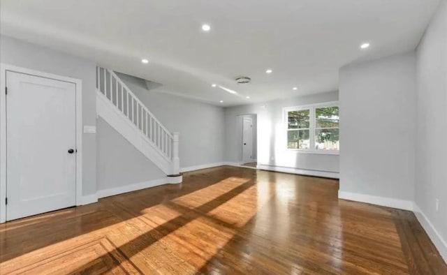 unfurnished living room with stairway, wood finished floors, a baseboard radiator, baseboards, and recessed lighting