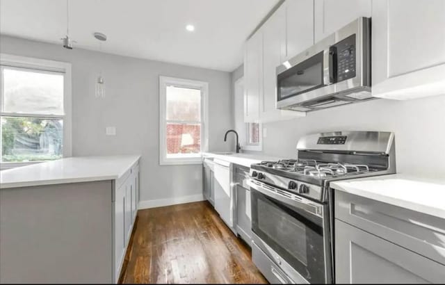 kitchen featuring dark wood-type flooring, light countertops, a sink, and appliances with stainless steel finishes