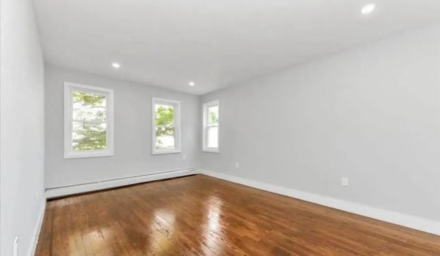 empty room with hardwood / wood-style flooring, baseboards, a baseboard heating unit, and recessed lighting