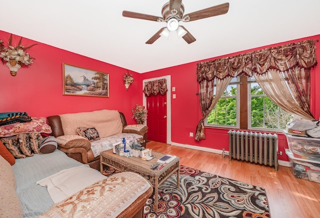 living area with wood finished floors, a ceiling fan, baseboards, lofted ceiling, and radiator heating unit