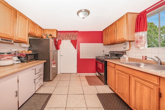 kitchen featuring a sink, tasteful backsplash, light tile patterned flooring, light countertops, and range with gas cooktop