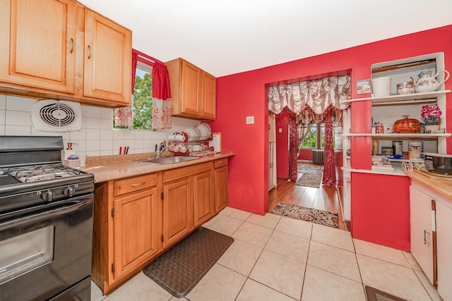kitchen featuring light countertops, tasteful backsplash, black range with gas cooktop, and a sink