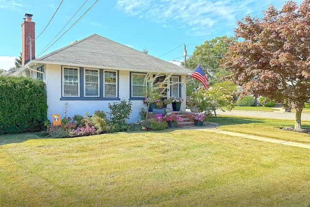 view of front of property with a front lawn, stucco siding, and a chimney