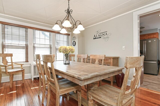 dining space with light wood-style flooring, crown molding, and an inviting chandelier
