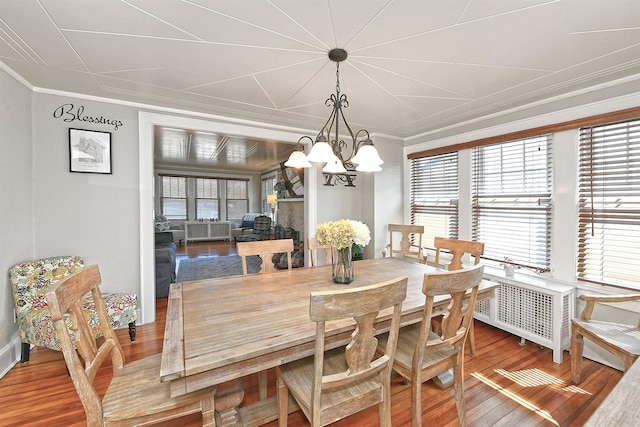 dining area with crown molding, wood finished floors, and a notable chandelier