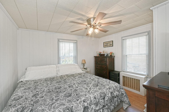 bedroom with ceiling fan, radiator, and wood finished floors