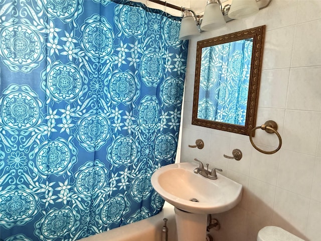 full bath with a shower with shower curtain, toilet, a sink, a chandelier, and tile walls