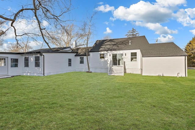 rear view of house featuring roof with shingles and a yard