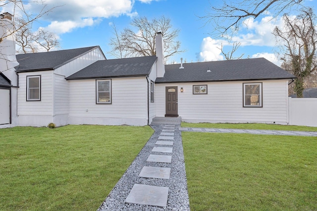view of front of property featuring a chimney, a shingled roof, fence, and a front lawn