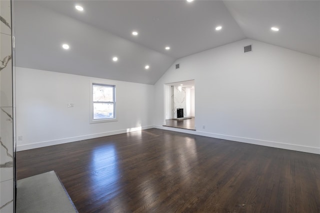 unfurnished living room featuring dark wood-type flooring, baseboards, vaulted ceiling, and visible vents