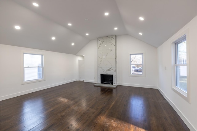 unfurnished living room with dark wood-type flooring, a fireplace, baseboards, and vaulted ceiling