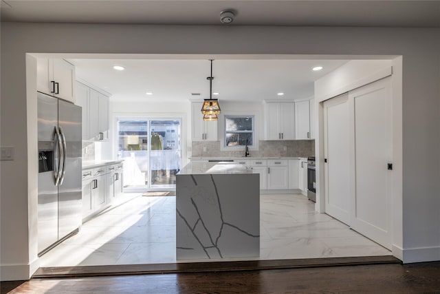 kitchen with stainless steel appliances, decorative backsplash, marble finish floor, a kitchen island, and white cabinets