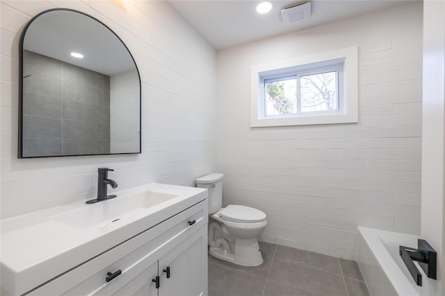 bathroom featuring tile patterned flooring, vanity, tile walls, toilet, and visible vents