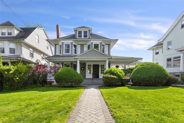 view of front of house featuring covered porch, a chimney, roof with shingles, and a front lawn