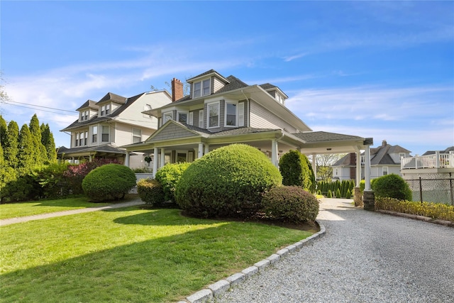 american foursquare style home featuring fence, a shingled roof, and a front yard