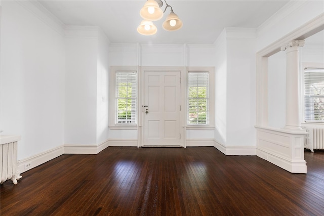 entrance foyer with radiator, hardwood / wood-style floors, baseboards, ornate columns, and a notable chandelier