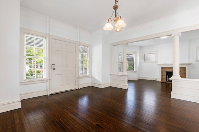 entrance foyer with a fireplace, dark wood finished floors, a chandelier, baseboards, and ornate columns