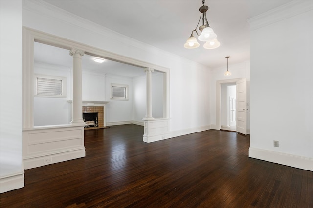 unfurnished living room with baseboards, ornate columns, wood finished floors, and a chandelier