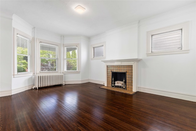 unfurnished living room with radiator heating unit, baseboards, a tiled fireplace, and wood finished floors