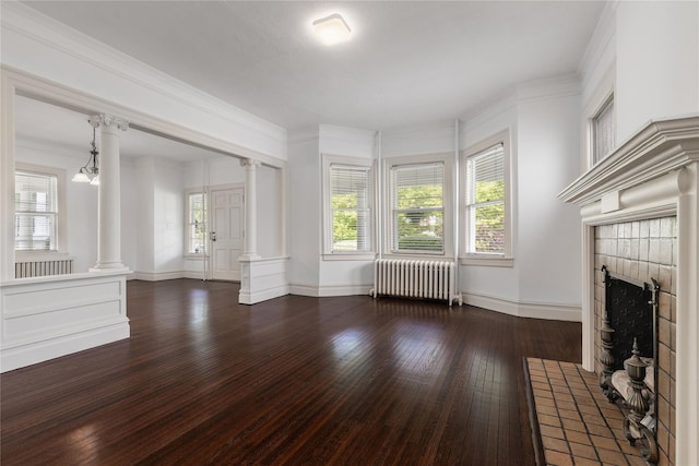 unfurnished living room featuring radiator, hardwood / wood-style floors, a fireplace, baseboards, and ornate columns