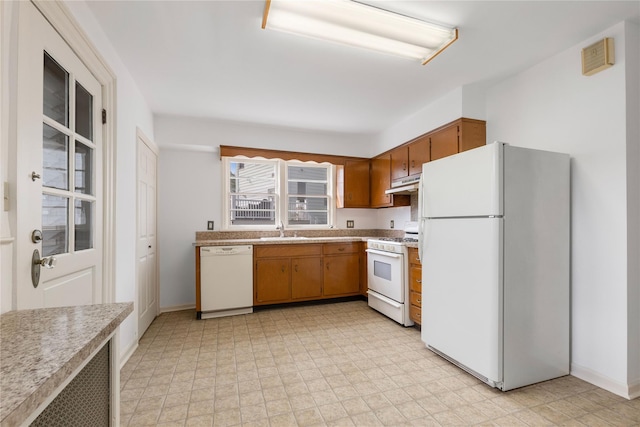 kitchen with brown cabinets, a sink, white appliances, light countertops, and under cabinet range hood